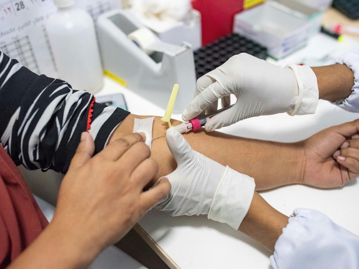 A phlebotomist drawing a blood sample from a patient's arm with a butterfly needle