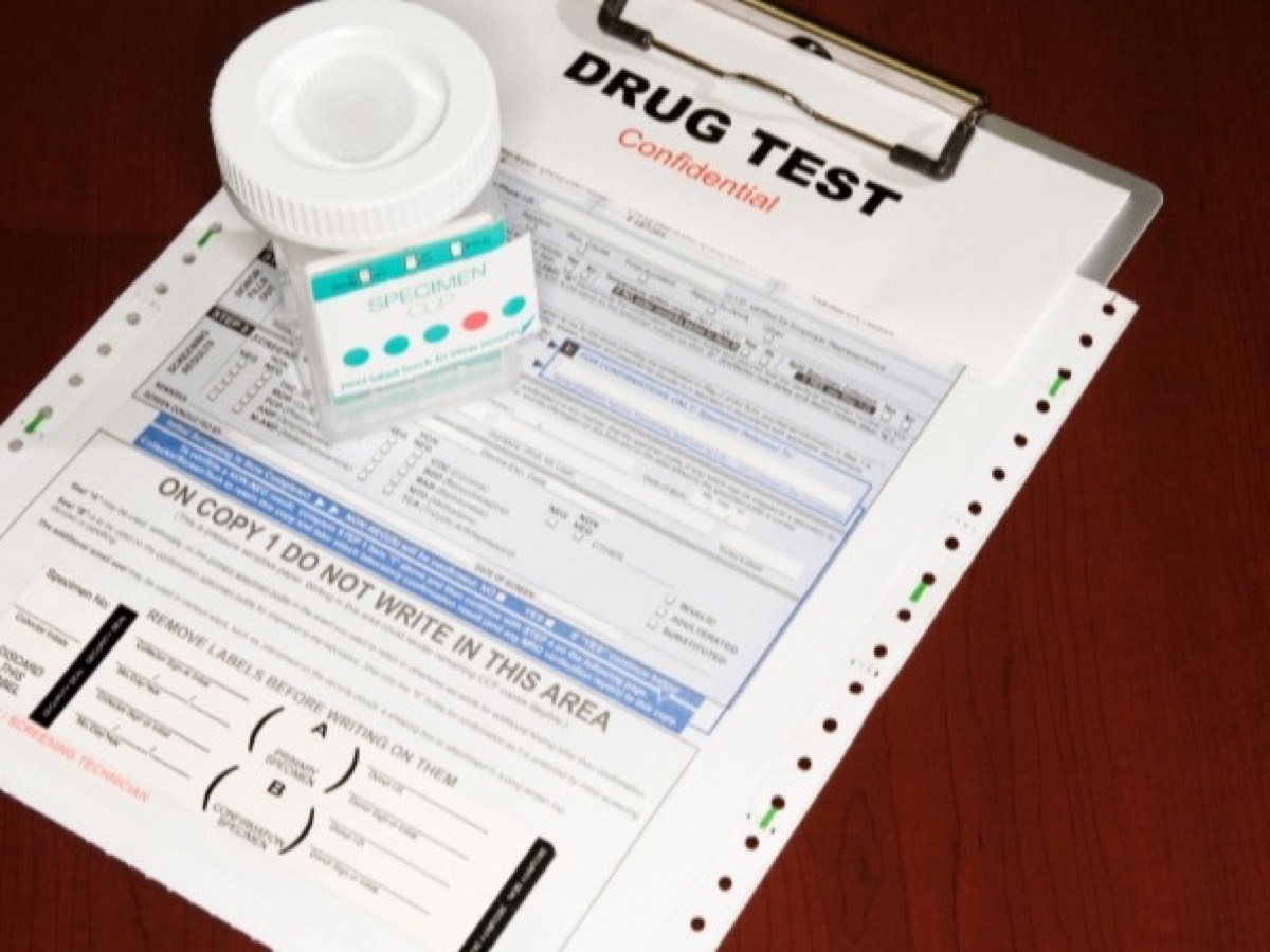 A sealed specimen cup resting on a drug test chain-of-custody form